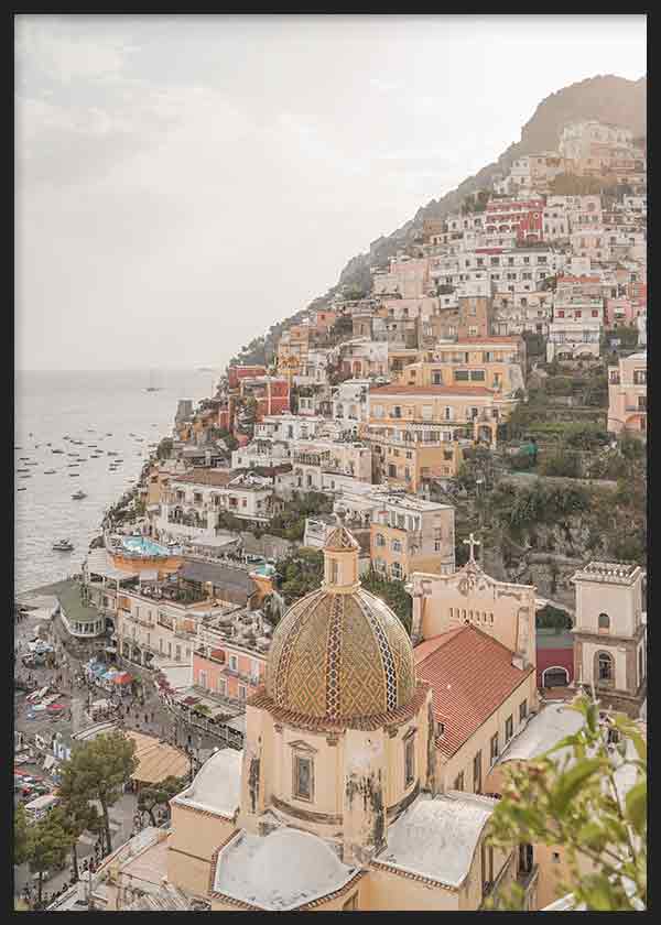 Cuadro de paisaje urbano costero de Positano con casas escalonadas, cúpula mediterránea, mar suave en tonos arena, blanco, terracota y azul grisáceo, de estilo fotográfico. Disponible en kudeko.com