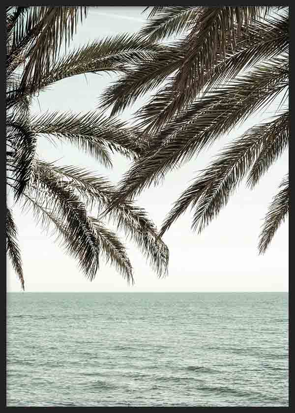 Cuadro con ramas de palmera oscuras sobre el mar tranquilo, cielo claro y tonos beige, marrones y azul verdoso, de estilo fotográfico. Disponible en kudeko.com