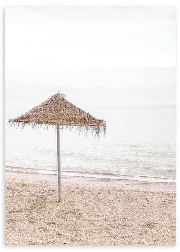 Tableau représentant une ombrelle en paille solitaire sur la plage, avec sable clair, mer beige et gris doux, et style photographique apaisant et épuré. Disponible sur kudeko.com