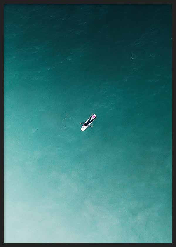 Cuadro de surfista solitario sobre tabla blanca en mar turquesa y verde azulado, con composición aérea de estilo fotográfico. Disponible en kudeko.com