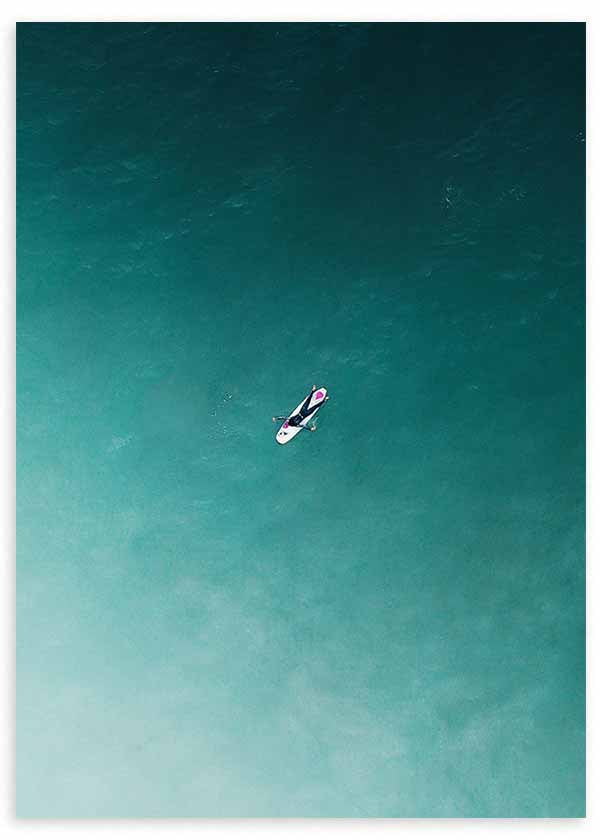 Cuadro de surfista solitario sobre tabla blanca en mar turquesa y verde azulado, con composición aérea de estilo fotográfico. Disponible en kudeko.com