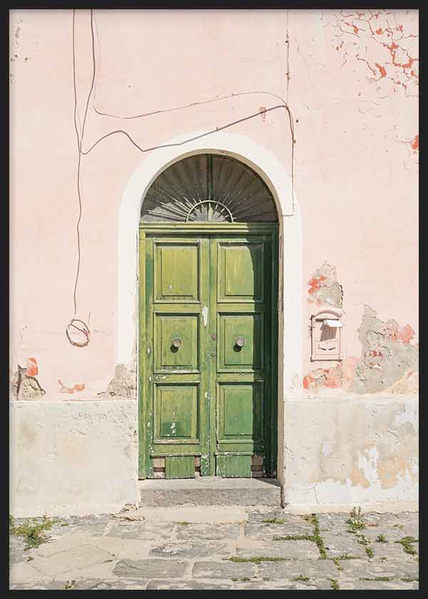 Cuadro de puerta antigua verde con arco blanco, fachada rosa desgastada, pared texturizada y suelo de piedra, de estilo fotográfico. Disponible en kudeko.com