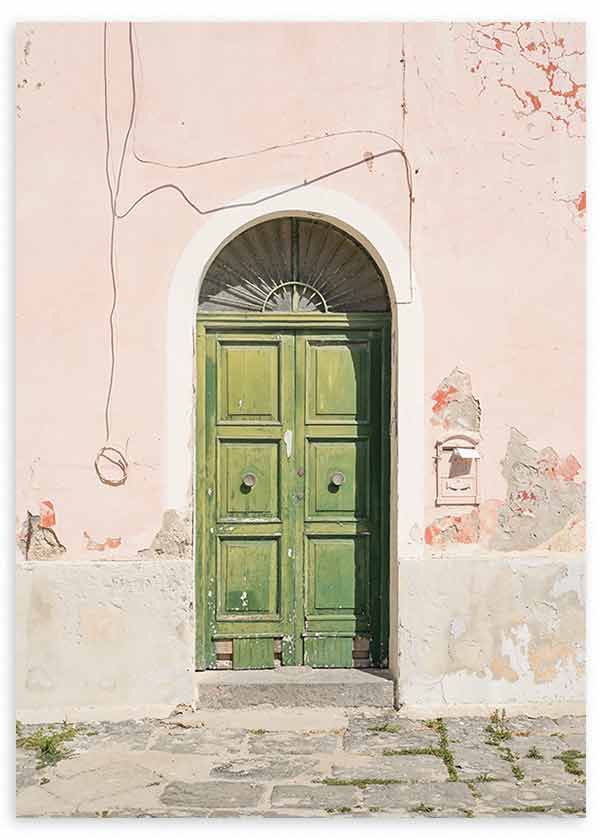 Cuadro de puerta antigua verde con arco blanco, fachada rosa desgastada, pared texturizada y suelo de piedra, de estilo fotográfico. Disponible en kudeko.com