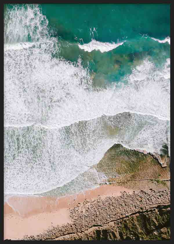 Cuadro con vista aérea del mar turquesa, olas blancas, arena beige y rocas costeras, de estilo fotográfico sereno y natural. Disponible en kudeko.com