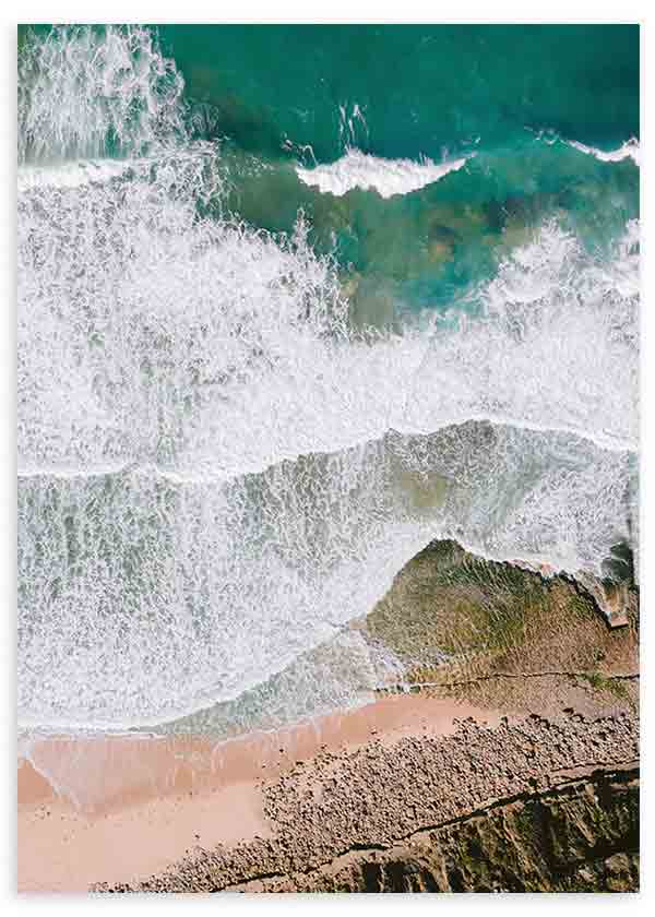 Quadro com vista aérea do mar turquesa, ondas brancas, areia bege e rochas costeiras, num estilo fotográfico natural e sereno para decoração de parede. Disponível em kudeko.com