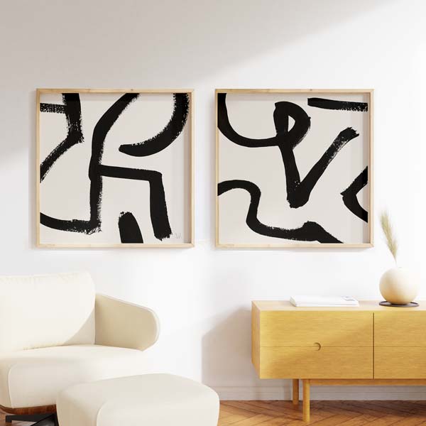 Ensemble de deux tableaux encadrés avec lignes courbes noires épaisses sur fond blanc cassé, composition abstraite contrastée au style minimaliste et contemporain. Disponible sur kudeko.com