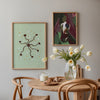 Gerahmtes Wandbild mit kleinen dunkelbraunen Blüten, geschwungenen Stielen, mintgrünem Hintergrund, weißen Details und orangefarbenen Akzenten in floralem, ruhigem Stil. Erhältlich auf kudeko.com