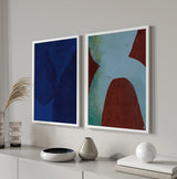 Cuadro abstracto con formas curvas azuladas sobre fondo rojo terroso, en marco negro, kudeko.com
