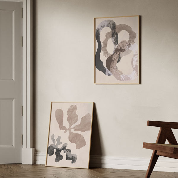 Set aus zwei Wandbildern mit organischen abstrakten Formen in Beige, Sand, Grau und Schwarz, fließende Komposition auf hellem Hintergrund, abstrakter Stil für moderne Wandgestaltung. Erhältlich auf kudeko.com