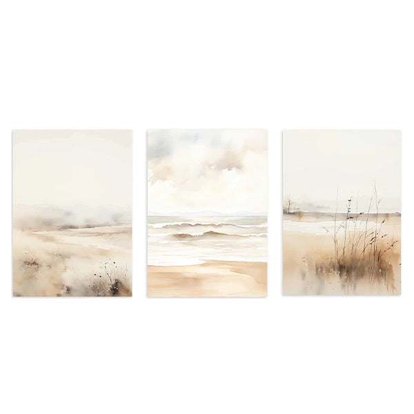 Set aus drei Wandbildern mit Sandstrand, ruhigem Meer, sanftem Küstennebel, Dünengräsern sowie Beige, Off-White und Hellgrau im Natur- und Landschaftsstil. Erhältlich auf kudeko.com