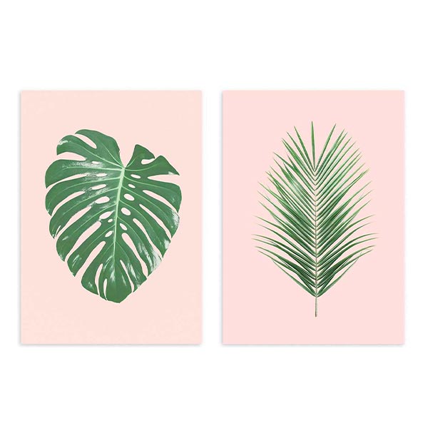 Ensemble de deux tableaux encadrés avec feuille de monstera et palme stylisée vertes sur fond rose poudré, style floral contemporain et lignes épurées. Disponible sur kudeko.com