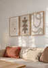 Set aus drei Wandbildern mit geschwungenen abstrakten Formen, weichen Linien, Halbkreisen und Kreisen in Beige, Sand und hellem Braun, im minimalistischen Stil. Erhältlich auf kudeko.com