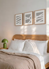 Set aus drei Wandbildern mit abstrakten Formen aus breiten weißen Linien auf taupegrauem Hintergrund, klare und ausgewogene Komposition im zeitgenössischen minimalistischen Stil. Erhältlich auf kudeko.com