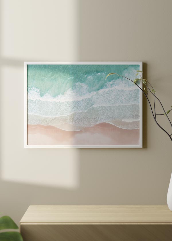 Cuadro horizontal con vista aérea de mar turquesa, espuma blanca y arena rosada, composición luminosa de estilo fotográfico inspirada en la costa. Disponible en kudeko.com