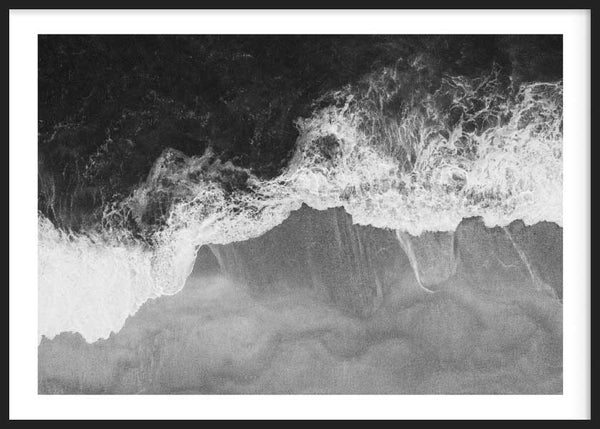 Quadro horizontal de mar em vista aérea com ondas de espuma branca, água escura, areia cinzenta e estilo preto e branco minimalista. Disponível em kudeko.com