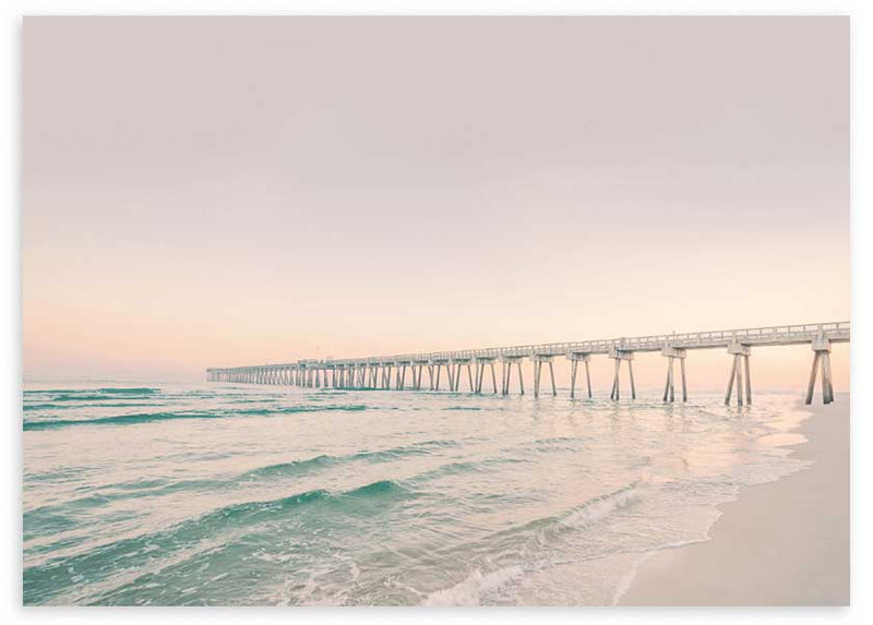 Cuadro horizontal de un muelle sobre el mar con olas suaves, arena clara, cielo rosado y tonos turquesa, de estilo fotográfico. Disponible en kudeko.com