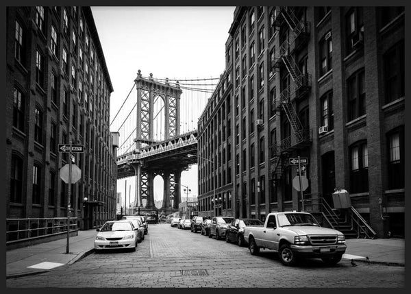 Cuadro horizontal de calle adoquinada en Brooklyn con puente de Manhattan, edificios de ladrillo, coches estacionados y tonos blanco y negro, de estilo ciudades. Disponible en kudeko.com