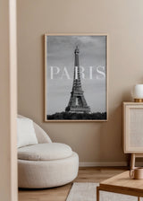 Gerahmtes Wandbild mit Eiffelturm, grauem Wolkenhimmel, weißer PARIS Typografie und urbaner Komposition in Schwarz, Weiß und Grautönen im Städte Stil. Erhältlich auf kudeko.com