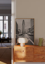 Quadro emoldurado de avenida urbana a preto e branco com edifício triangular, carros em movimento, perspetiva central e estilo fotográfico arquitetónico. Disponível em kudeko.com