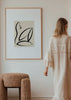 Gerahmtes Wandbild mit abstrakter weiblicher Silhouette in schwarzen Linien auf hellbeigem Hintergrund, elegantem minimalistischem Stil und ruhiger moderner Wirkung. Erhältlich auf kudeko.com