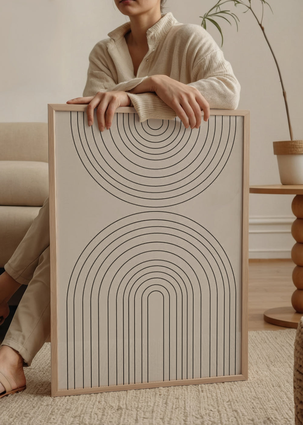 Gerahmtes Wandbild mit schwarzen konzentrischen Bögen auf hellbeigem Hintergrund, symmetrischer Komposition, klaren Linien und zeitgenössischem geometrischem Stil für eine schlichte Wandgestaltung. Erhältlich auf kudeko.com