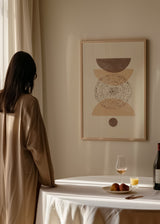 Tableau encadré avec formes géométriques courbes superposées, cercle central pointillé, petite forme ronde, tons beige, sable, blanc cassé et brun taupe, style abstrait bohème. Disponible sur kudeko.com