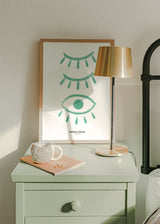 Quadro emoldurado com olhos fechados e um olho aberto em verde água sobre fundo branco, composição simbólica em estilo ilustração com linhas suaves contemporâneas. Disponível em kudeko.com