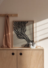 Cuadro decorativo de estilo minimalista y abstracto colocado en salón, líneas orgánicas fluidas en negro sobre fondo beige, modelo Fluyendo III