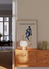 Gerahmtes Wandbild mit abstrakter menschlicher Figur in Marineblau, beigem Hintergrund, organischen senfgelben Formen und schwarzer Typografie im minimalistischen Stil. Erhältlich auf kudeko.com