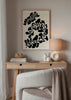 Gerahmtes Wandbild mit schwarzen botanischen Formen, geschwungenen organischen Blättern auf cremefarbenem Hintergrund, minimalistischer Komposition, klarem Kontrast und zeitgenössischem Stil. Erhältlich auf kudeko.com