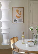 Gerahmtes Wandbild mit Illustration von drei Bananen in sanftem Orange, Creme und Beige, beigem Hintergrund, klarer Komposition und schwarzer Typografie im minimalistischen Editorial-Stil. Erhältlich auf kudeko.com