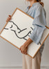 Gerahmtes Wandbild mit weiblicher Silhouette in schwarzen Linien auf weißem Hintergrund, schlichte Komposition, minimalistische Ästhetik und moderne Gestaltung für ruhige Wohnräume. Erhältlich auf kudeko.com