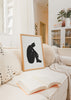 Gerahmtes Wandbild mit sitzender weiblicher Silhouette in Schwarz auf weißem Hintergrund, klaren Linien, starkem Kontrast, ruhiger Komposition und minimalistischem Stil. Erhältlich auf kudeko.com