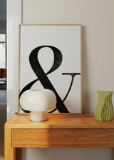 Quadro com grande símbolo ampersand preto sobre fundo branco, tipografia elegante, contraste marcado, textura subtil e estilo minimalista contemporâneo. Disponível em kudeko.com