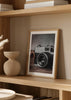 Tableau avec appareil photo rétro au premier plan sur surface en bois, tons gris, noirs et bruns, style vintage élégant et nostalgique. Disponible sur kudeko.com