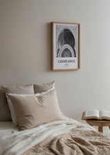 Quadro com arco monumental de arquitetura marroquina, relevos ornamentais, mosaicos geométricos e tons de branco, cinzento e preto, num estilo fotográfico elegante e urbano. Disponível em kudeko.com