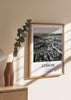 Quadro emoldurado com vista aérea de Lisboa, edifícios urbanos compactos junto ao rio, tons preto, branco e cinzento, estilo fotográfico elegante e contemporâneo. Disponível em kudeko.com