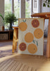 Tableau avec oranges entières et tranches sur fond beige, dans des tons orange, terre cuite et vert doux, au style minimaliste et décoratif. Disponible sur kudeko.com