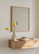 Gerahmtes Wandbild mit menschlicher Figur, Mondphasen in Beige, Weiß und Grau auf hellem Hintergrund, minimalistische und surrealistische Komposition. Erhältlich auf kudeko.com