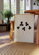 Wandbild mit fünf schwarzen Blumen, abgerundeten Blütenblättern, feinen Stielen, hellbeigem Hintergrund und klarer Komposition im minimalistischen Stil. Erhältlich auf kudeko.com
