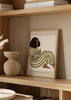 Quadro com mulher sentada de perfil, macacão às riscas creme e pretas, fundo bege claro, detalhes castanho terra e estilo de ilustração contemporânea para decoração de parede. Disponível em kudeko.com