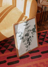 Tableau encadré avec branches d’eucalyptus aux feuilles arrondies en vert grisé, blanc et gris doux, dans une composition botanique légère de style nature et paysage. Disponible sur kudeko.com