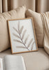 Cuadro decorativo de estilo minimalista y orgánico colocado en salón, rama botánica en tonos grises suaves, modelo Rama Gris