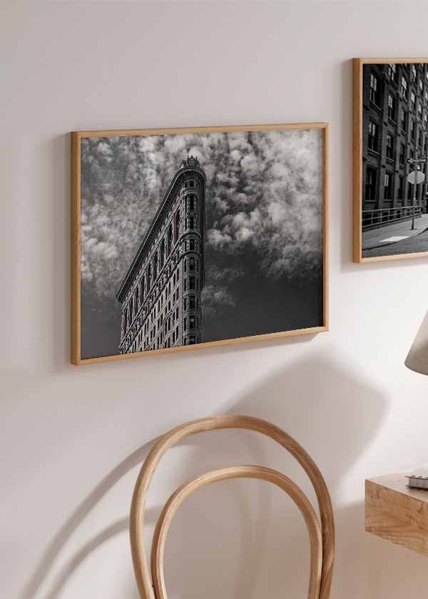 Horizontales Wandbild eines klassischen Gebäudes an schmaler Ecke, in Untersicht fotografiert, mit dramatischem Wolkenhimmel in Grau, Schwarz und Weiß, im urbanen architektonischen Stil. Erhältlich auf kudeko.com