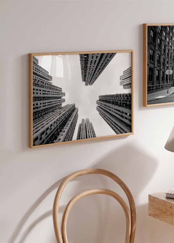 Cuadro horizontal de rascacielos en perspectiva ascendente, con fachadas grises, cielo blanco amplio, composición urbana simétrica y estilo fotográfico en blanco y negro. Disponible en kudeko.com