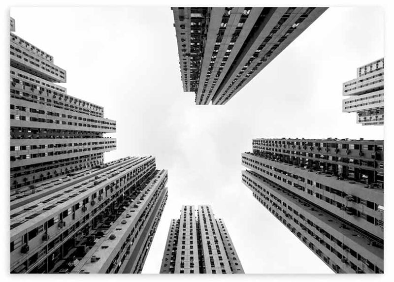 Cuadro horizontal de rascacielos en perspectiva ascendente, con fachadas grises, cielo blanco amplio, composición urbana simétrica y estilo fotográfico en blanco y negro. Disponible en kudeko.com