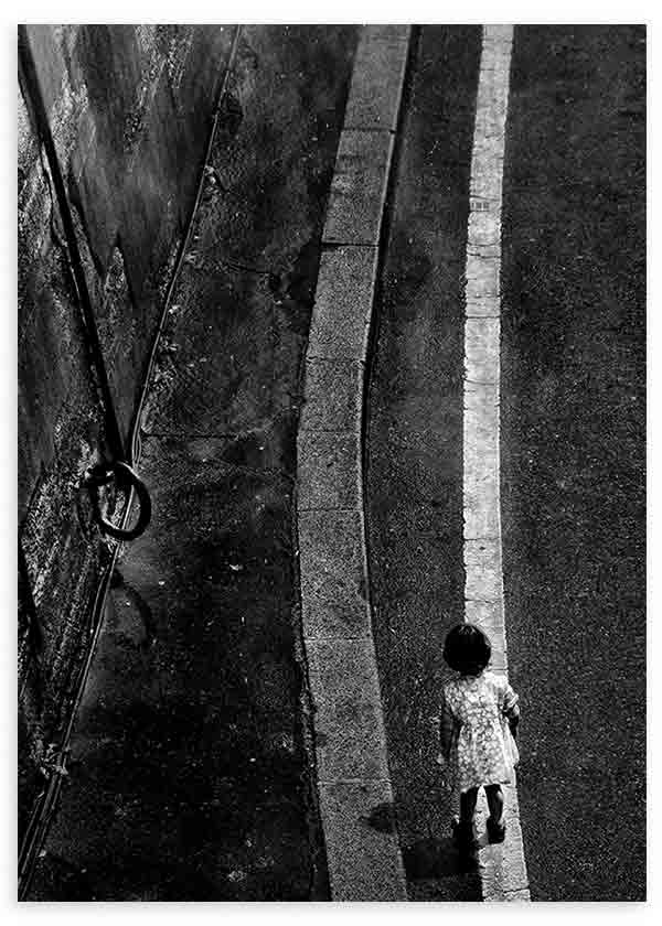 Tableau de scène urbaine en noir et blanc avec personne solitaire marchant près d’une ligne blanche sur asphalte sombre, aux textures marquées et au style photographique contemporain. Disponible sur kudeko.com