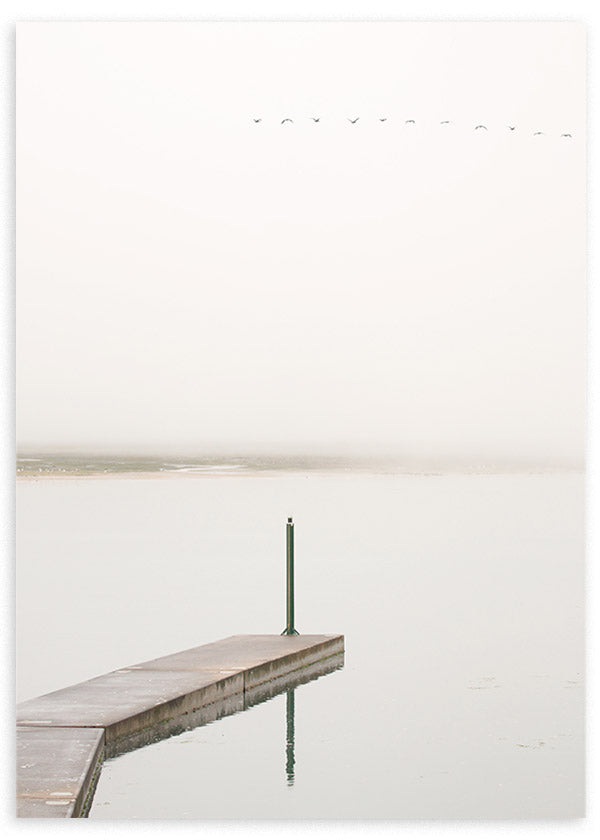 Cuadro de paisaje costero con muelle de cemento sobre agua tranquila, cielo brumoso, aves lejanas y tonos blanco roto, gris suave y beige, de estilo naturaleza y paisajes. Disponible en kudeko.com