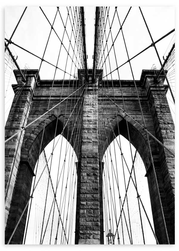 Wandbild der Brooklyn Bridge in Schwarz-Weiß, mit Steinbögen, gespannten Kabeln, Untersicht, symmetrischer Komposition und urbanem fotografischem Architekturstil. Erhältlich auf kudeko.com