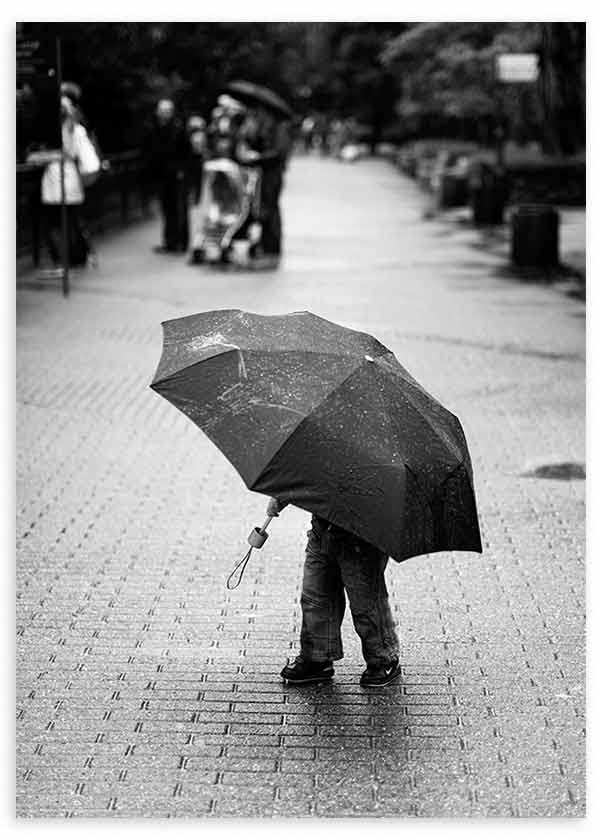 Cuadro de escena urbana lluviosa con persona bajo paraguas negro, suelo mojado en tonos grises y fondo desenfocado, de estilo fotográfico. Disponible en kudeko.com